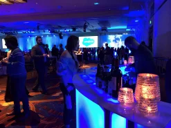 Signature Series Curved LED Bar Station for Corporate Brand Activations. Curved modular portable bar with blue LED lighting serving guests at a large corporate networking event.