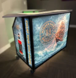 Fusion 48 Lighted Portable Bar with Custom Nautical Theme Distillery Branding Fusion 48 lighted portable bar on casters featuring custom LED illuminated wrap graphics for Hidden Ships Distillery.